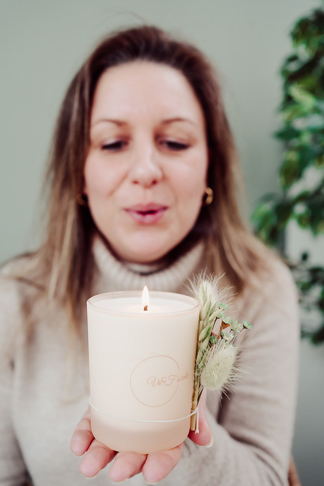 Vrouw houdt V&F Scents Forêt geurkaars in crème pot vast met droogbloemen