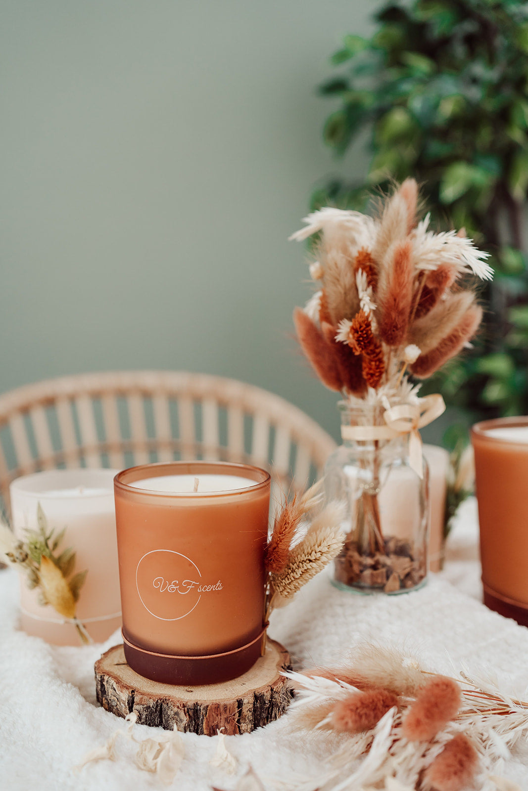 V&F Scents geurkaars in oranje glazen pot op houten schijf met droogbloemen